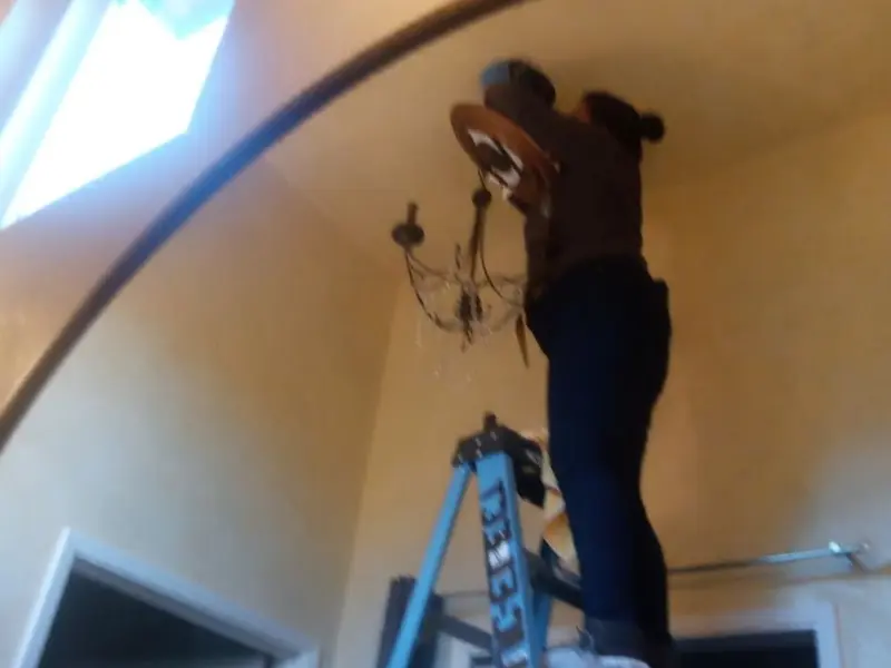 Electrician installing a chandelier in a Seekonk residence